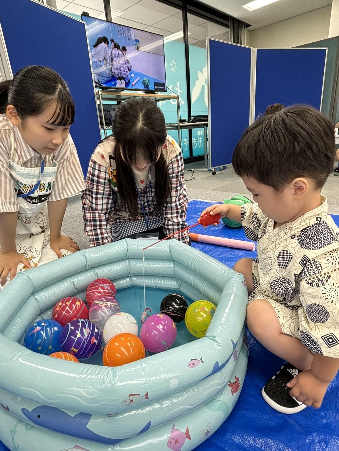 子どもと一緒にヨーヨー釣りをしている生徒